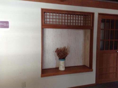 a window with a plant in a vase on a wall at Happokan in Hakuba