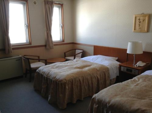 a hotel room with two beds and two windows at Happokan in Hakuba