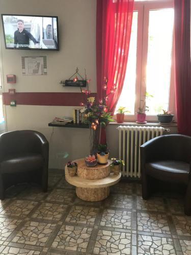 a waiting room with two chairs and a table and a tv at Au Royal Hotel in Carcassonne