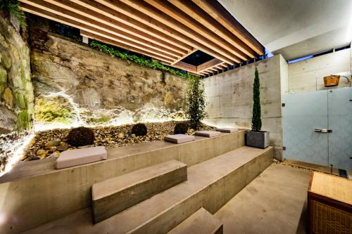 a bathroom with three benches and a rock wall at Parkhotel Graz - Traditional Luxury in Graz