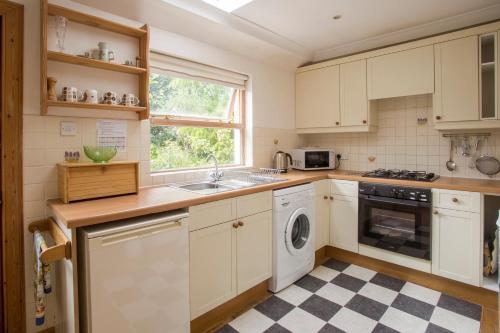 una cucina con armadi bianchi, lavandino e lavastoviglie di Woodcroft Cottage ad Ayr