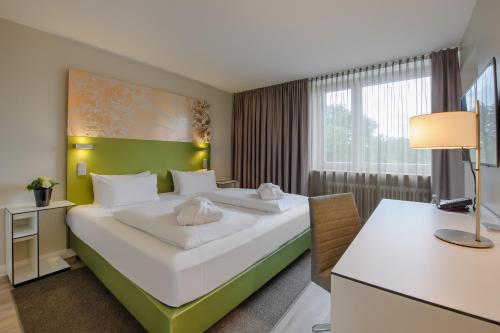 a hotel room with a large bed and a desk at Congress Hotel Mercure Nürnberg an der Messe in Nürnberg