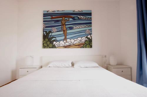 une chambre avec un lit blanc et un tableau au mur dans l'établissement Casa Silencio, Villa with terrace, garden and large pool area, à Corralejo