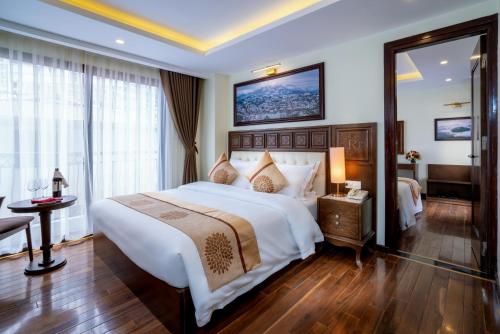 a bedroom with a large white bed and a mirror at Sapa Relax Hotel & Spa in Sa Pa