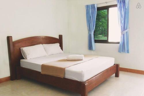 a bedroom with a bed with blue curtains and a window at Thai Muang Resort in Thai Muang