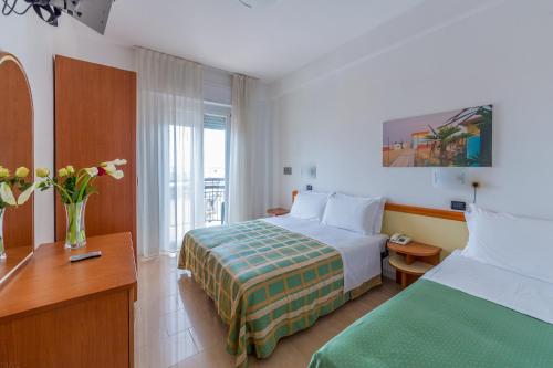リミニにあるHotel Sultanoのベッド、デスク、ベッドが備わるホテルルームです。