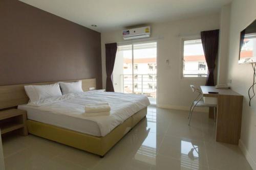 a bedroom with a large bed and a desk and window at U Place Korat in Nakhon Ratchasima