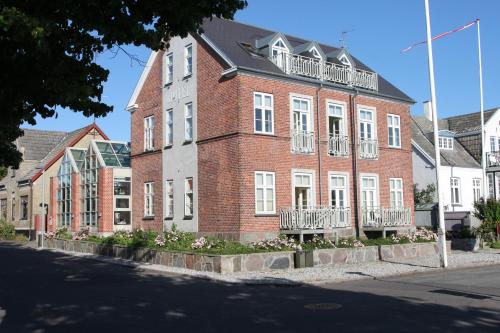 un gran edificio de ladrillo rojo con ventanas blancas y balcones en Hotel Nysted Havn, en Nysted