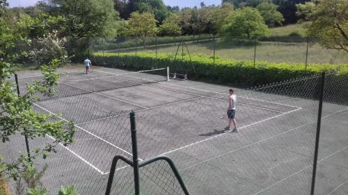 dos hombres jugando al tenis en una pista de tenis en Camping 46 Rainettes, en Goujounac