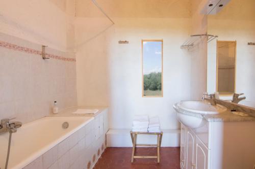 La salle de bains blanche est pourvue d'une baignoire et d'un lavabo. dans l'établissement Château de Chanteraine, à Aiguines
