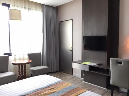 a hotel room with a bed and a desk and a tv at Gallery Design - SHA Extra Plus in Si Sa Ket