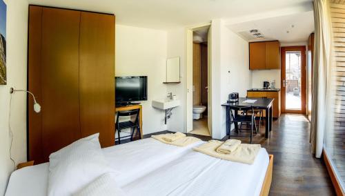 a bedroom with a large white bed and a kitchen at Hotel Sanje ob Soči ***/**** in Bovec