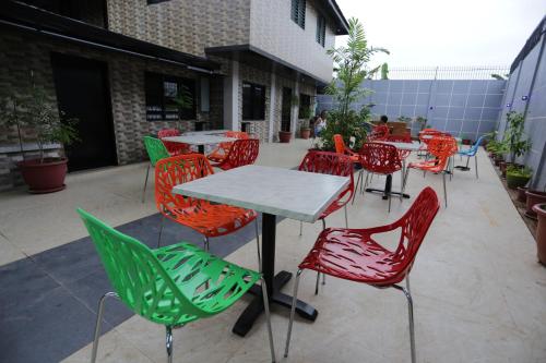 a group of tables and colorful chairs on a patio at HalfWay House Hostel Mactan Cebu Airport in Mactan