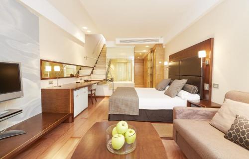 a hotel room with a bed and a living room at Insotel Fenicia Prestige Suites & Spa in Santa Eularia des Riu