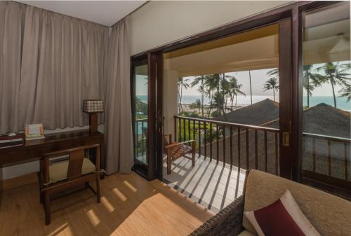 a living room with a desk and a balcony at Eskala Hotels and Resorts in Ngwesaung
