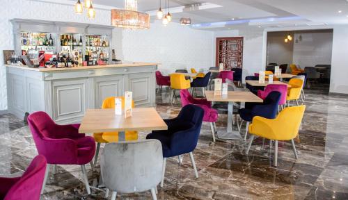 a restaurant with wooden tables and colorful chairs at Royal Class Hotel in Cluj-Napoca