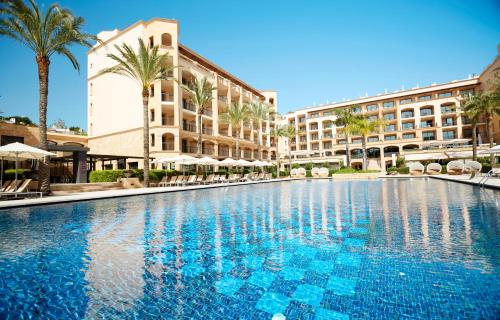 una piscina en un complejo con palmeras y edificios en Insotel Fenicia Prestige Suites & Spa en Santa Eulalia del Río