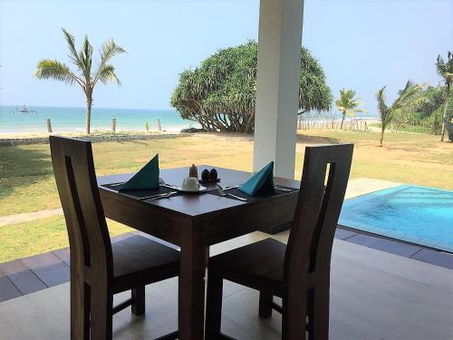 a wooden table and chairs with a view of the beach at The Pleasure Kosgoda in Bentota