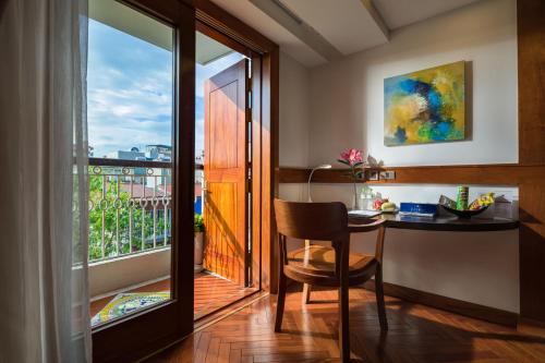 a room with a desk and a balcony with a window at Hai Bay Hotel & Restaurant in Hanoi
