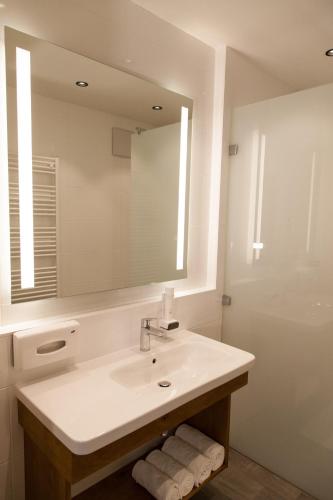 a white bathroom with a sink and a mirror at Landgasthof Barenwirt in Petzenkirchen