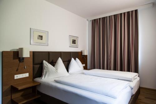 a bedroom with a bed with white sheets and pillows at Landgasthof Barenwirt in Petzenkirchen