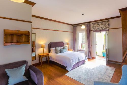een slaapkamer met een bed en 2 stoelen bij Eendracht Hotel in Stellenbosch