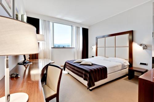 a bedroom with a bed and a desk and a lamp at Italiana Hotels Cosenza in Cosenza