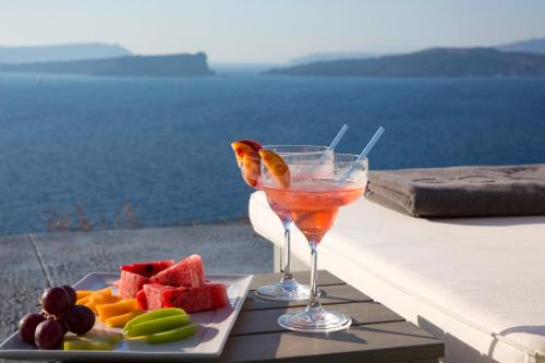 a drink and a plate of fruit on a table at Akrotiri Cove in Akrotiri