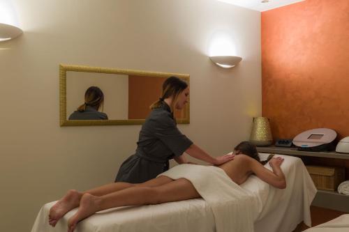 a woman getting a massage from a woman laying on a bed at Borgo La Chiaracia Resort & SPA in Castel Giorgio