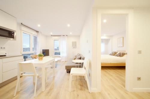 Habitación blanca con cama, mesa y sillas en Mirador a Poniente en Gijón