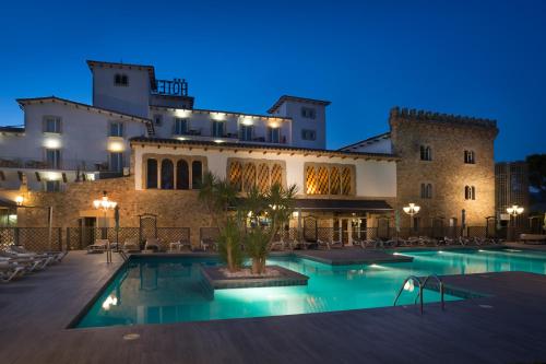 a hotel with a swimming pool in front of a building at Hotel Castell Blanc in Empuriabrava