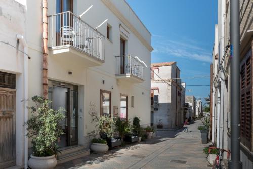 a street with white buildings and potted plants at Hotel Biancolilla in San Vito lo Capo