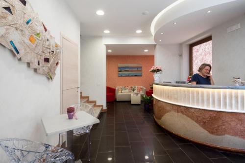 a woman sitting at a bar in a room at Hotel Biancolilla in San Vito lo Capo
