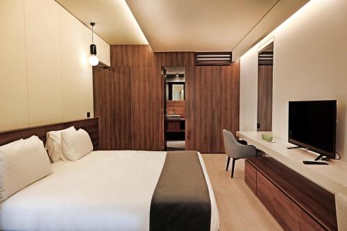 a bedroom with a bed and a desk with a television at Le Pave Hotel in Bayt al Kūkū