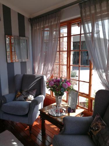 a living room with two chairs and a table with flowers at Van Dykshuis Guest House in Heidelberg