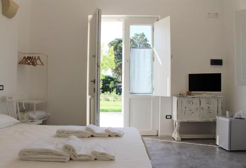a white bedroom with a bed with towels on it at Podere 43 Charme B&B in Otranto
