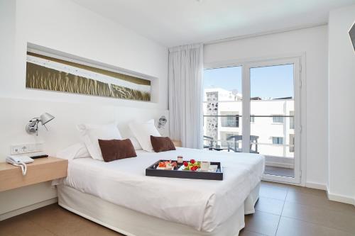 ein Hotelzimmer mit einem Bett und einem Tablett mit Essen darauf in der Unterkunft Ibiza Sun Apartments in Playa d'en Bossa