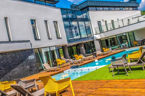 a building with a swimming pool with yellow chairs at Open Hotel Szentes in Szentes