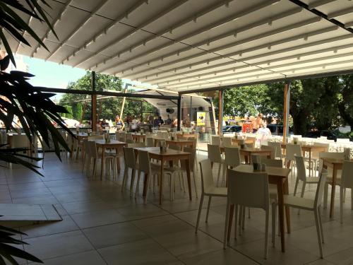 Ein Restaurant mit Tischen und Stühlen und Menschen im Hintergrund in der Unterkunft Gladiola 3-star in Goldstrand
