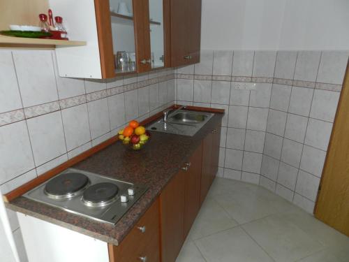 a kitchen with a sink and a bowl of fruit on a counter at Apartmani Lucija Jurković in Malinska