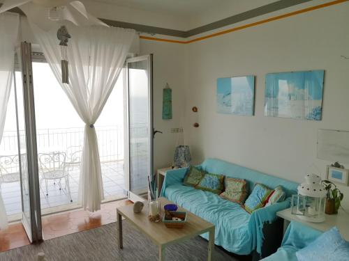 un soggiorno con divano blu e balcone di Taormina Rising Sun Apt a Forza dʼAgro