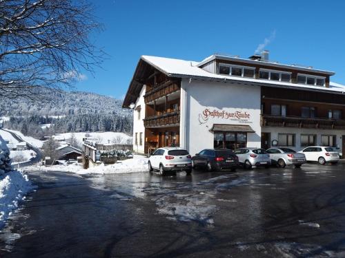 ein großes Gebäude mit Autos auf einem Parkplatz in der Unterkunft Pension & Gasthof zur Taube in Sulzberg