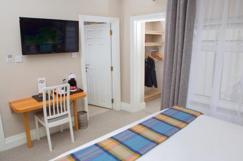 a bedroom with a bed and a desk and a tv at McMunns of Ballybunion in Ballybunion