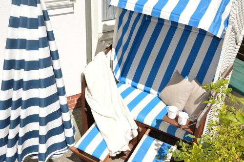 a blue and white striped chair and umbrella on a patio at Appartement-Villa Steinfurth in Binz