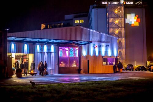 a group of people standing outside of a building at night at Hotel Swiss Star in Wetzikon