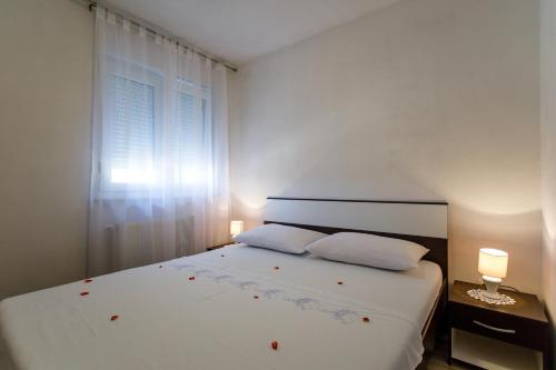 a bedroom with a white bed with two pillows and a window at Apartman Dobrila in Vrh