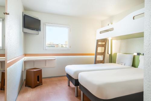 a hotel room with two beds and a tv at ibis budget Paris Porte de Bercy in Charenton-le-Pont