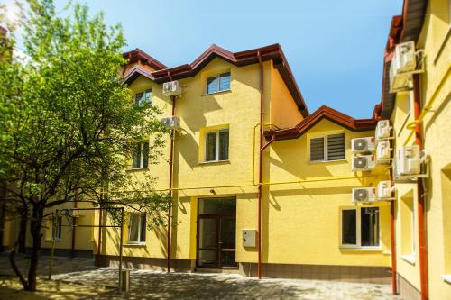 un edificio amarillo con un árbol delante de él en Blum Hotel en Leópolis