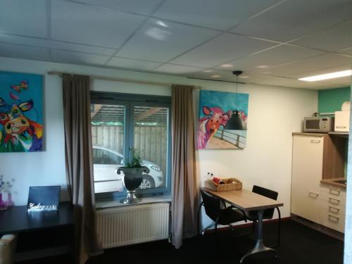 ein Büro mit einem Schreibtisch, einem Tisch und einem Fenster in der Unterkunft Appartement De Molshoop II in Landsmeer