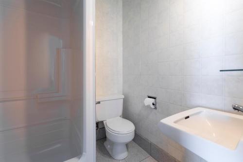 La salle de bains blanche est pourvue de toilettes et d'un lavabo. dans l'établissement Auberge des Berges, à Saint-Félicien